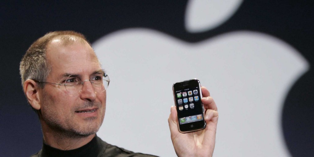 Steve Jobs holding up an early iPhone